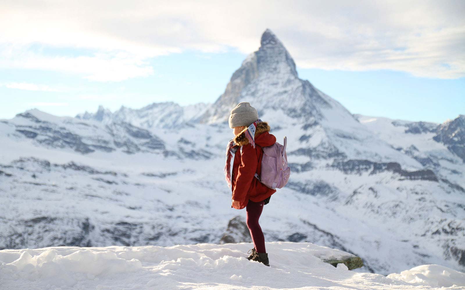image of young girl standing nthe snow with a mountain in the background